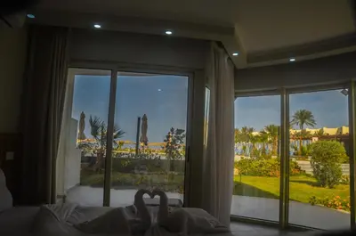 two swans laying on a bed in front of a window at Scandic resort سكانديك ريزورت in Hurghada