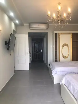 a bedroom with two beds and a television and a chandelier at Scandic resort سكانديك ريزورت in Hurghada