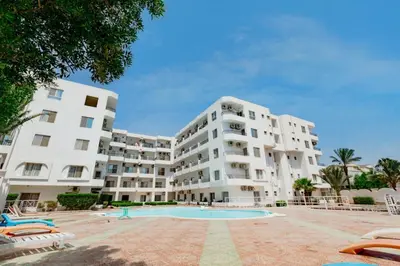 a large white apartment building with a swimming pool at Al makramia compound in Hurghada