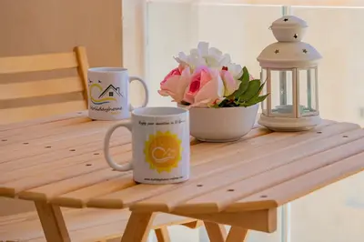 a wooden table with two coffee mugs and a vase of flowers at Modern apartment with large pool & beach access in Hurghada