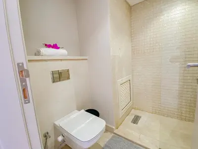 a bathroom with a white toilet and a shower at Modern apartment with large pool & beach access in Hurghada