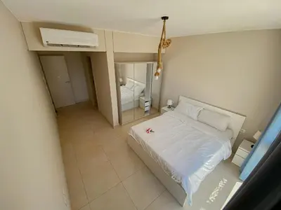 a bedroom with a white bed and a mirror at Modern apartment with large pool & beach access in Hurghada