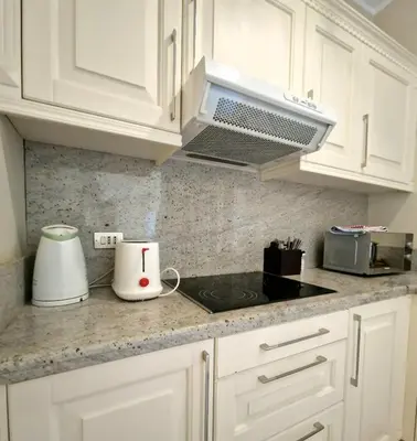 a kitchen with white cabinets and a stove top oven at Nubian Style Apartment, South Marina, El Gouna in Hurghada