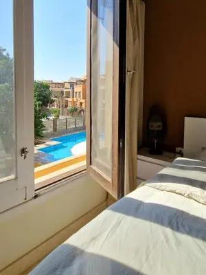 a bedroom with a window with a view of a swimming pool at Nubian Style Apartment, South Marina, El Gouna in Hurghada