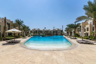 a large swimming pool with chairs and umbrellas at Modern apartment with great Pool & Beach access in Hurghada