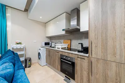 a kitchen with wooden cabinets and a stove at Modern apartment with great Pool & Beach access in Hurghada