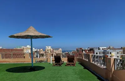 a patio with chairs and an umbrella on a roof at Oriental Tail Home in Hurghada