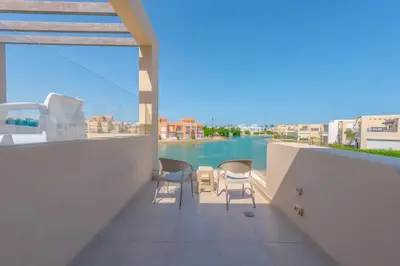 a balcony with chairs and a view of the water at Elegant 4BR in Tawila, Gouna. Private Pool, Lagoon in Hurghada