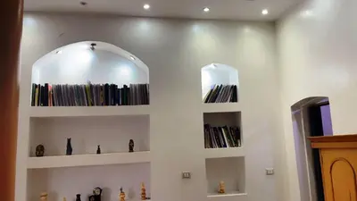 a room with shelves filled with books and a mirror at El Hady Apartments with Swimming Pool in Luxor