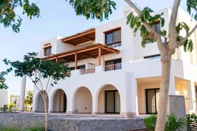 a white building with trees in front of it at Makadi Heights Elite Worldwide Residences - Hurghada, Egypt in Hurghada