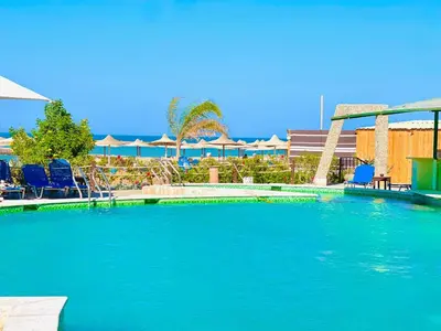 a large swimming pool with blue chairs and umbrellas at Luna Blu Sea View in Hurghada