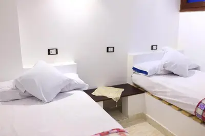 two beds with white pillows and a table in a room at Magic Place Luxor in Luxor