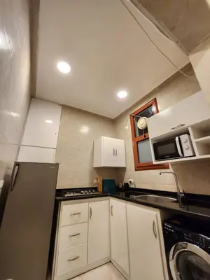a small kitchen with white cabinets and a microwave at Wa set Luxor Apartment in Luxor