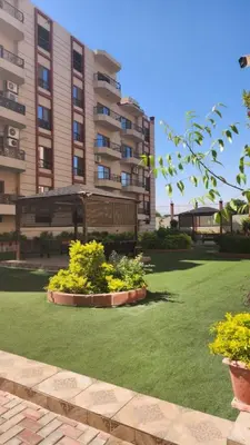 a large building with some plants in a yard at Wa set Luxor Apartment in Luxor
