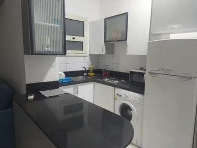a white kitchen with a washing machine and a washer at one bed Apartment In Al Makramia in Hurghada
