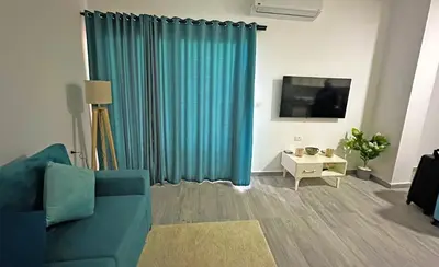 a living room with a blue couch and a tv at Imperial Resort Apt Sleeps 3 - Pool Parking Wifi in Hurghada