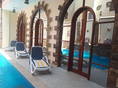 a room with a pool and chairs next to a building at Pyramids Luxor Hotel & SPA in Luxor