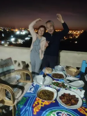 a man and woman standing in front of a table of food at Nubian Hights guesthouse in Shellal
