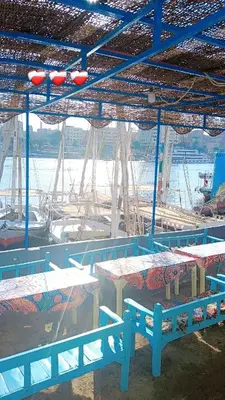 a group of tables and benches under a blue structure at Onaty Narty Guest house Nile view in Aswan