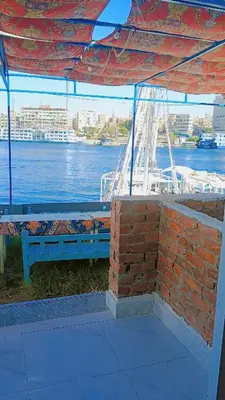 a blue bench sitting under a pavilion next to the water at Onaty Narty Guest house Nile view in Aswan