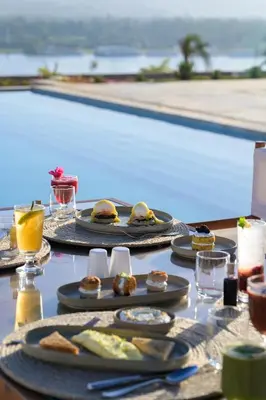 a table with plates of food next to a swimming pool at The Zen Wellness Resort in Aswan
