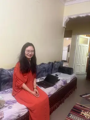 a woman sitting on a bed with a laptop at Alara Hostel 