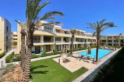 an apartment building with a swimming pool and palm trees at The Snuggly Studio G Cribs El Gouna in Hurghada