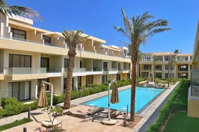 an apartment building with a swimming pool and palm trees at The Snuggly Studio G Cribs El Gouna in Hurghada