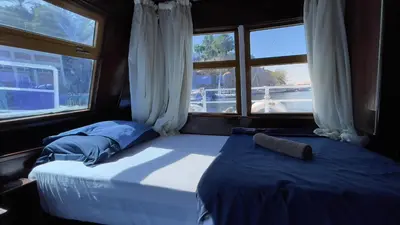 a bedroom with two beds and a window on a boat at Freedom Houseboat in Aswan