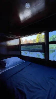 a bedroom with a bed and two windows on a boat at Freedom Houseboat in Aswan