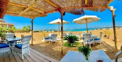 a patio at the beach with tables and umbrellas at Turtles Beach resort hourghada Studio view sea view pool private beach Pools balcony security Cafe and restaurant on pool jacuzzi air-condition sunny a large balcony in Hurghada