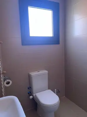 a bathroom with a toilet and a blue window at Baywest Villa, Somabay in Safaga
