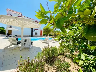 a patio with two chairs and an umbrella and a pool at Villa 6 in Hurghada