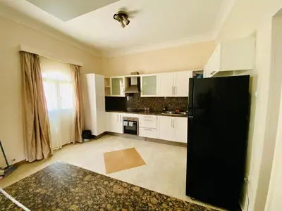 a kitchen with white cabinets and a black refrigerator at Villa 6 in Hurghada