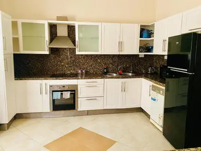 a kitchen with white cabinets and a black refrigerator at Villa 6 in Hurghada