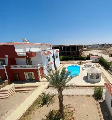 a house with a palm tree and a swimming pool at Villa 6 in Hurghada