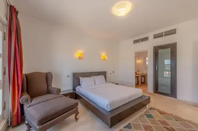 a bedroom with a bed and a chair at Golf Luxury villa with private pool in Hurghada