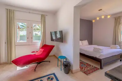 a bedroom with a bed and a red chair at Golf Luxury villa with private pool in Hurghada