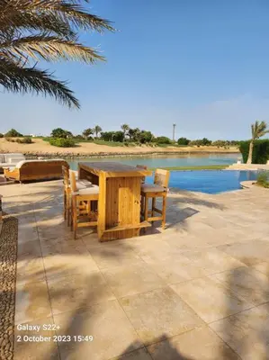 a wooden table and chairs next to a body of water at Golf Luxury villa with private pool in Hurghada