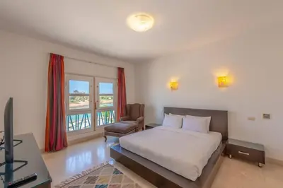a bedroom with a bed and a chair and a television at Golf Luxury villa with private pool in Hurghada