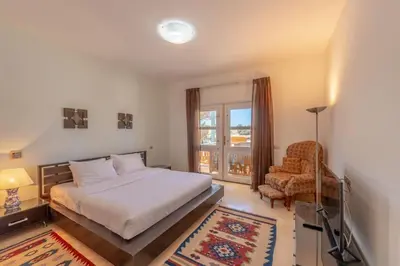 a bedroom with a bed and a chair and a window at Golf Luxury villa with private pool in Hurghada