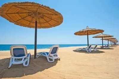 two beach chairs and umbrellas on the beach at The View Residence Studio in Hurghada