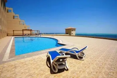 a swimming pool with two lounge chairs and the ocean at The View Residence Studio in Hurghada