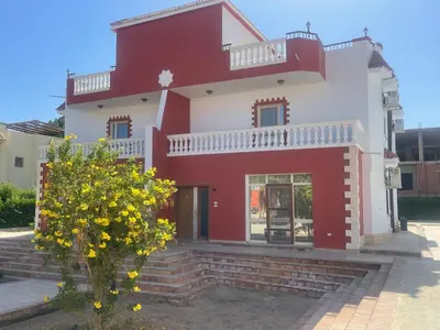 a red and white house with a tree in front at Hurghada-Magawish Villa 6 in Hurghada