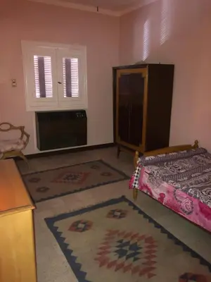 a bedroom with a bed and a kitchen with a window at Dr milad shokralla multiple central flats in Luxor