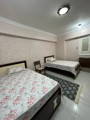 a bedroom with two beds and two chairs at Dr milad shokralla multiple central flats in Luxor
