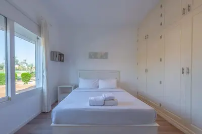 a white bedroom with a large bed with a window at unique flat_ garden and lagoon in Hurghada