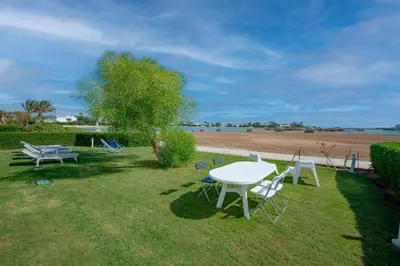 a table and chairs sitting on the grass near a beach at unique flat_ garden and lagoon in Hurghada