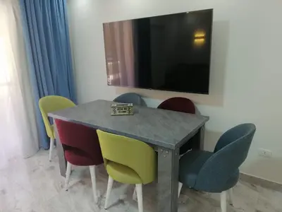 a dining room table with colorful chairs and a television at Selena Bay Resort & beach in Hurghada