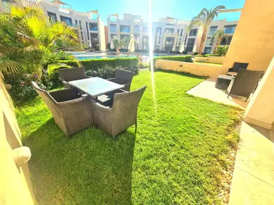 a patio with a table and chairs on the grass at Fabulous Sea view 1 BR & private Garden to the pool at Mangroovy in Hurghada
